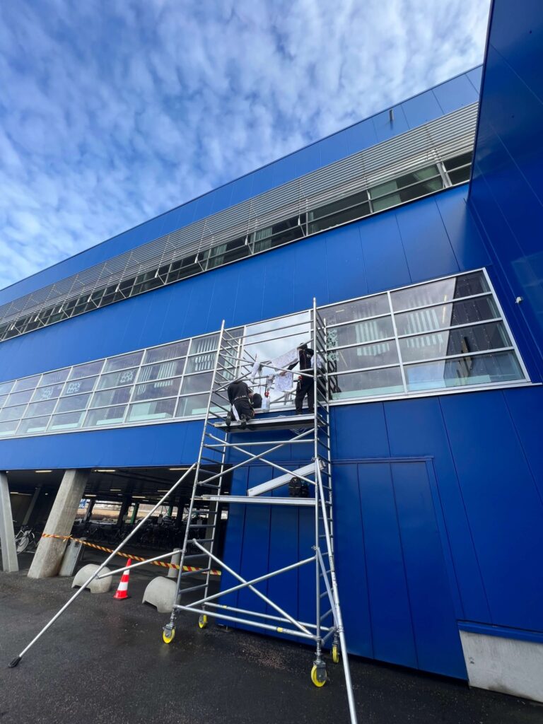 Arbetare installerar solfilm på IKEA byggnaden i Uppsala